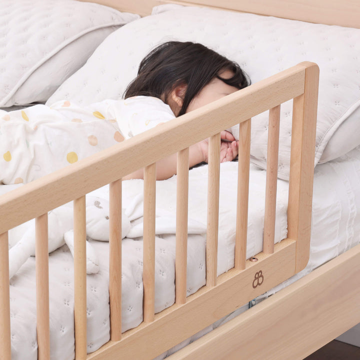 Baby sleeping on bed with side guard rail