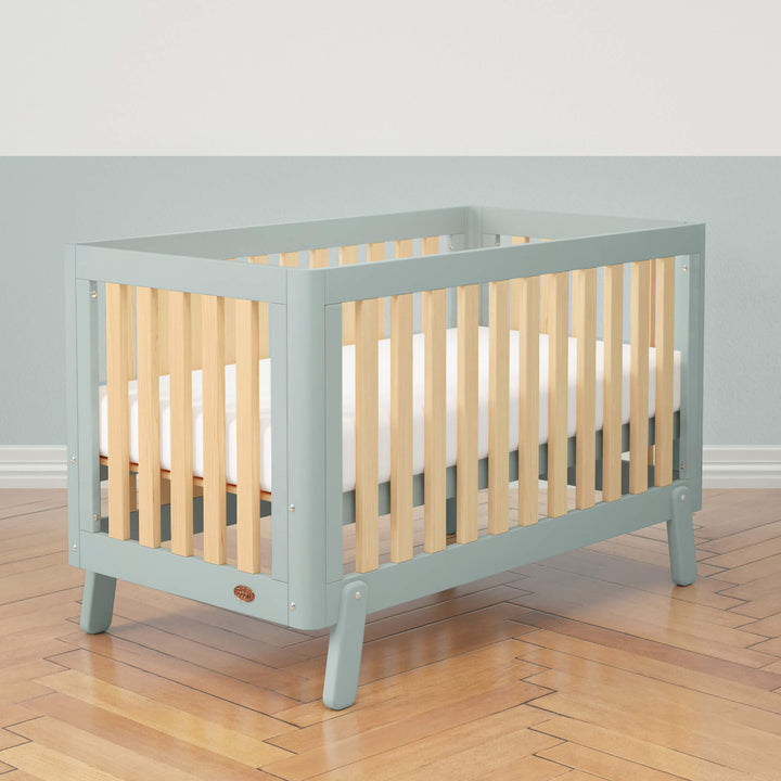blue cot bed with wooden spindles, rounded corners and feet