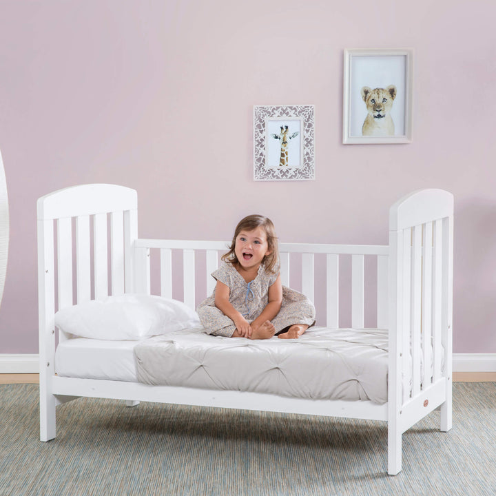toddler sitting on the White Alice Cot Bed 