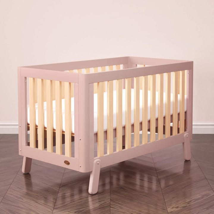 pink cot bed with wooden spindles, rounded corners and feet