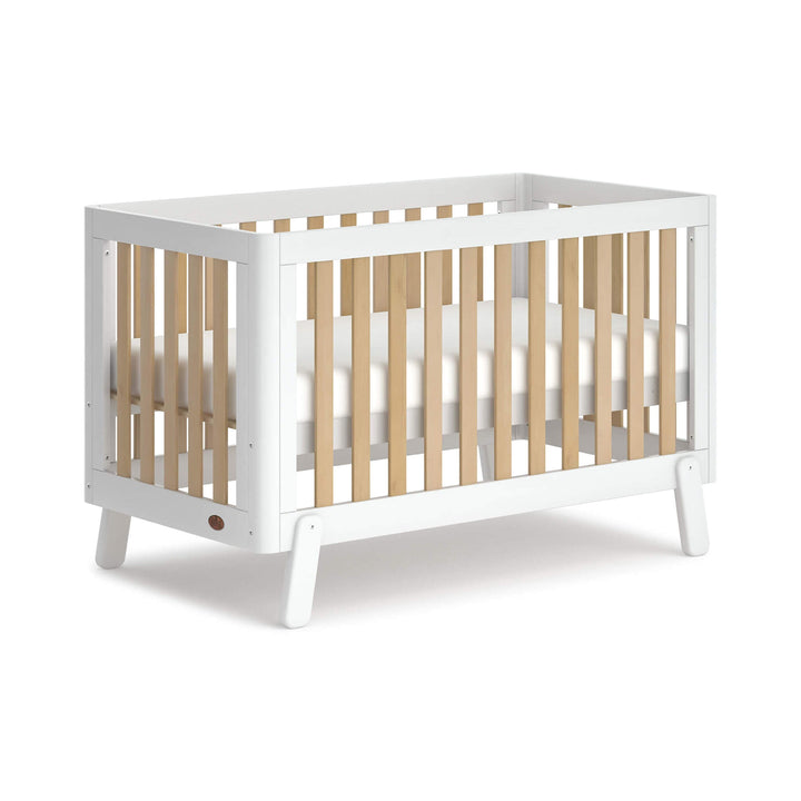 white cot bed with wooden spindles, rounded corners and feet