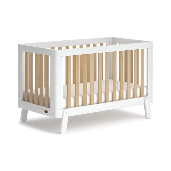 white cot bed with wooden spindles, rounded corners and feet